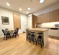 A kitchen with a bar counter, dining table, and a floor with a wood decor in a 2-room apartment.