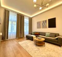 Living room in a two-room apartment with a wooden decor floor, gray sofa, and decorative paintings.