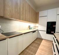 A kitchen with built-in appliances and a wooden decor floor in a 2-room apartment.