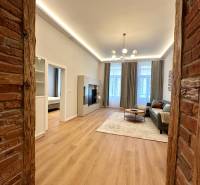 Living room in a two-room apartment with a wooden decor floor and a brick wall.