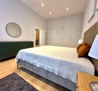 Bedroom in a two-room apartment with a bed, wardrobes, and a floor with a wooden decor.