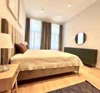 Bedroom in a 2-room apartment with a large bed, lamp, and floor with wood decor.