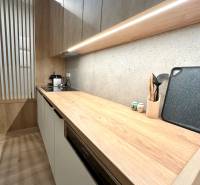 A kitchen unit in a 2-room apartment with a wooden decor and built-in appliances.