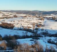 A snowy landscape of Hriňová in Zánemecká with scattered cottages, hills, and winter nature.