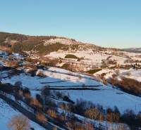 A snowy landscape with a cottage on Zánemecká Street in Hriňová, surrounded by hills.