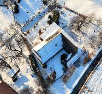 A snow-covered cottage on Zánemecká Street in Hriňová surrounded by trees and nature.