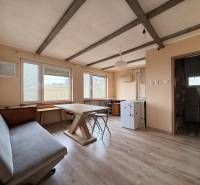 The interior of a cabin with a wooden decor floor, a table, and a couch.