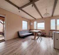Interior of a cabin with seating, a view of nature, and a floor with a wooden decor.