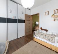 Children's room with a bed, built-in wardrobe, and wooden decor flooring in a 3-room apartment.