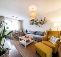 Living room in a 3-room apartment with plants, a yellow armchair, and a wooden decor floor.