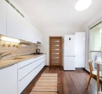 A bright kitchen in a 3-room apartment with white cabinets and a wood-patterned floor.