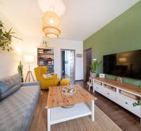 Living room in a 3-room apartment with a television, wooden decor flooring, and a comfortable armchair.