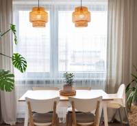 Dining area with a table, chairs, and a plant in a 3-room apartment with wooden decor flooring.
