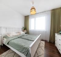 A bright bedroom with white furniture, wood-patterned flooring, and plants in a 3-room apartment.