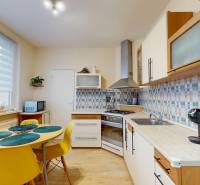 A kitchen in a 3-room apartment with a wooden decor floor and colorful tiles.