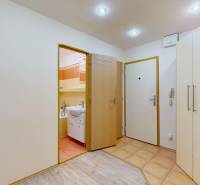 The entrance hall of a 3-room apartment with tiles, a built-in wardrobe, and a floor with a wooden decor.