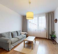 Living room in a three-room apartment with a wooden decor floor, a sofa, and a table.