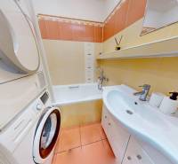 A bathroom with a sink, bathtub, and washing machine in a 3-room apartment.