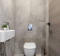 Compact toilet in a 3-room apartment with modern gray tiles and a small sink.