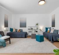 Bright living room in a three-room apartment with wood-patterned flooring and two sofas.