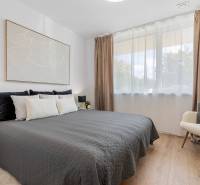 A bedroom in a 3-room apartment with a bed, an armchair, and a wooden decor floor.
