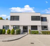 A building with a minimalist design, greenery, and a parking lot on Lipnicka Street in Dunajska Luzna.