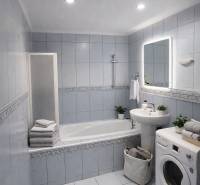 Bathroom in a 2-room apartment with a bathtub, sink, and washing machine, light tiles and decorations.