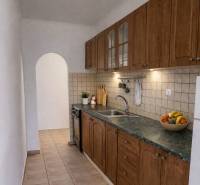 A narrow kitchen in a 2-room apartment with wooden cabinet decor and an arched doorway.