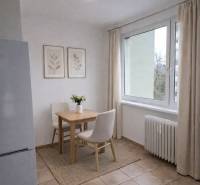 Dining area with two chairs in a 2-room apartment, light tiles, large window.