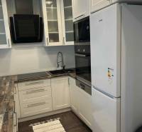 A kitchen in a 3-room apartment with white cabinets and a wood-patterned floor.