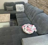Gray sofa with cushions by a stone wall in a 3-room apartment.