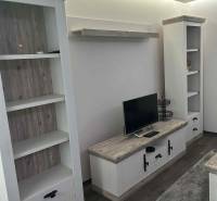 Living room in a 3-room apartment with shelves, a television, and a wooden decor floor.