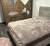 Bedroom of a 3-room apartment with a bed and a mirrored wardrobe on a wooden decor floor.