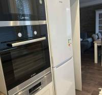 A kitchen in a 3-room apartment with modern appliances and a wooden decor floor.