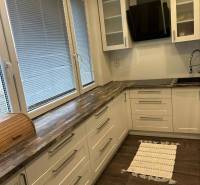 A kitchen in a 3-room apartment with a wooden decor floor and light cabinets.