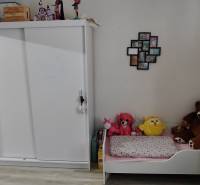 Children's room in a 3-room apartment with a white wardrobe, bed, and toys.
