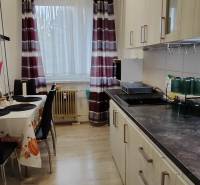 A kitchen in a 3-room apartment with a wooden decor floor and a dining table.