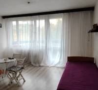 A room in a three-room apartment with a bed, table, chairs, and a floor with a wooden decor.