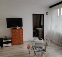 Living room in a 3-room apartment with a TV on a dresser and a table with two chairs.