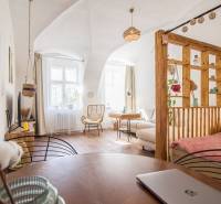 Interior of a 1-room apartment with a wood-decor floor, light, and cozy furniture.