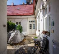 Entrance to the courtyard, colorful walls, flowers, chairs, and table. Obchodná, Bratislava - Old Town.
