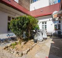 A garden in Bratislava on Obchodná Street with benches, a table, and a bush in front of the exchanger.