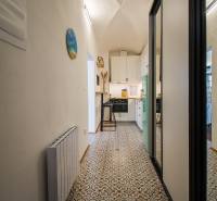 A hallway of a one-room apartment with a patterned floor, a mirrored wardrobe, and a kitchen at the end.