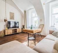 A living room with wood-patterned flooring and comfortable sofa seating in a studio apartment.