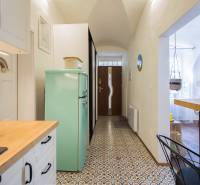 The kitchen of a one-room apartment with a mint refrigerator, a coffee maker, and a patterned floor.