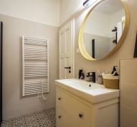 A bathroom in a studio apartment with a prominent round mirror and decorative tiles.