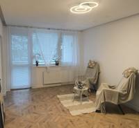 Living room in a 4-room apartment with a wooden decor floor, armchairs, and decorations.