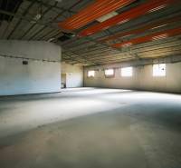 An empty interior of manufacturing premises with a concrete floor and windows on the walls.