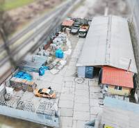 Production premises in Konská with cars and construction material near the railway track.