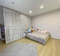 A room with sliding doors, a wooden decor floor, and a bed in a family house.